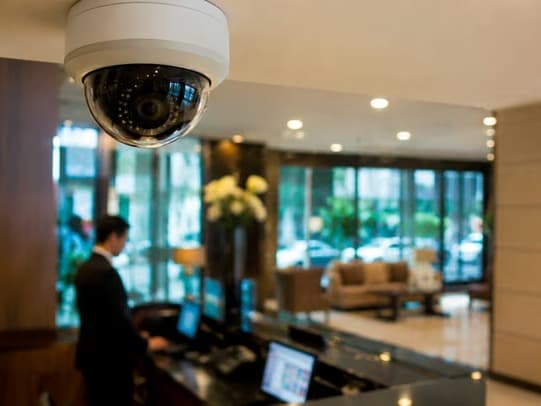 Cámara domo en el cielo del lobby de un hotel, con la recepción y la entrada vidriada a contraluz