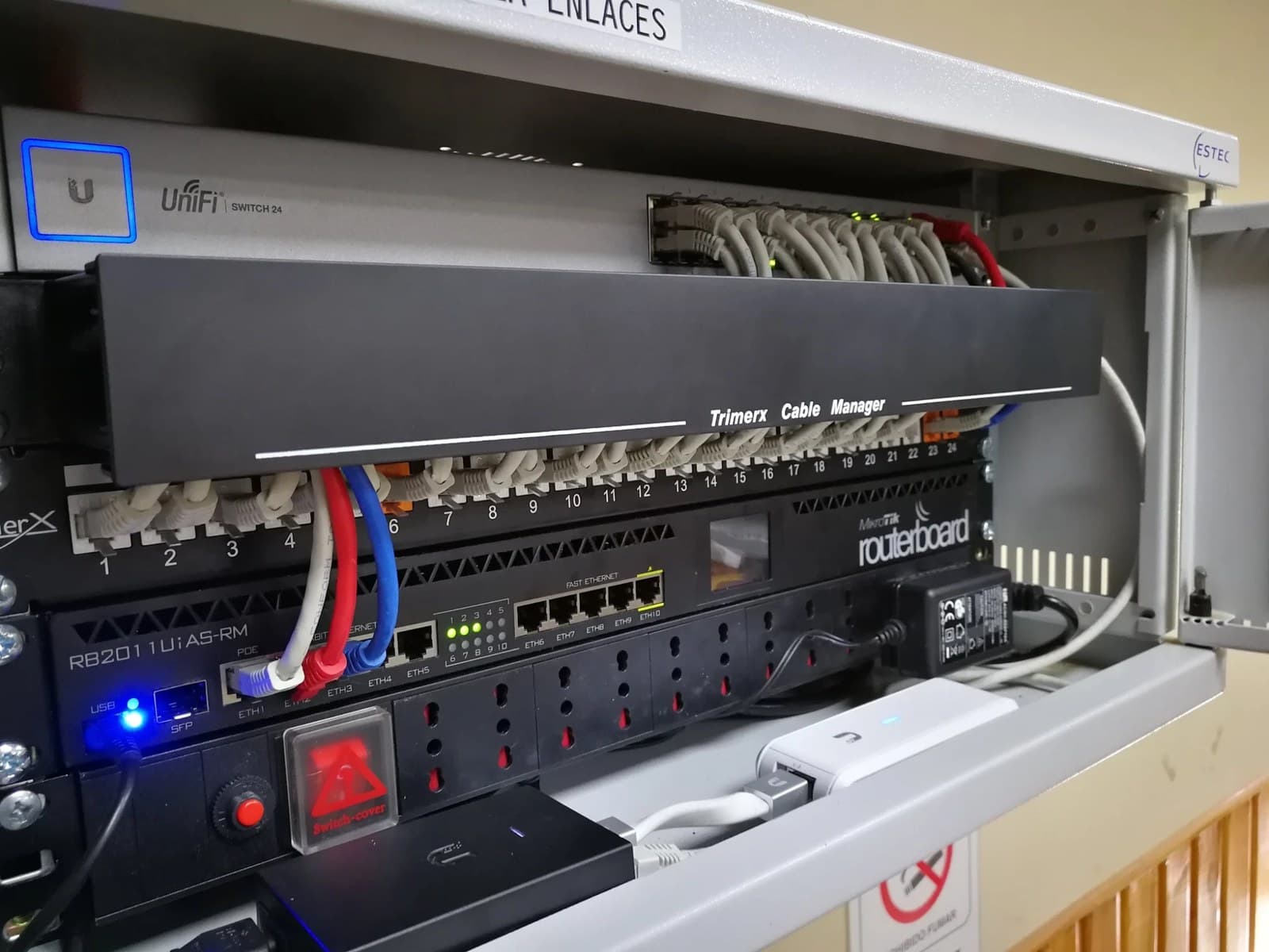 Patch panel con los puertos numerados y los cordones ordenados bajo el organizador, junto al switch