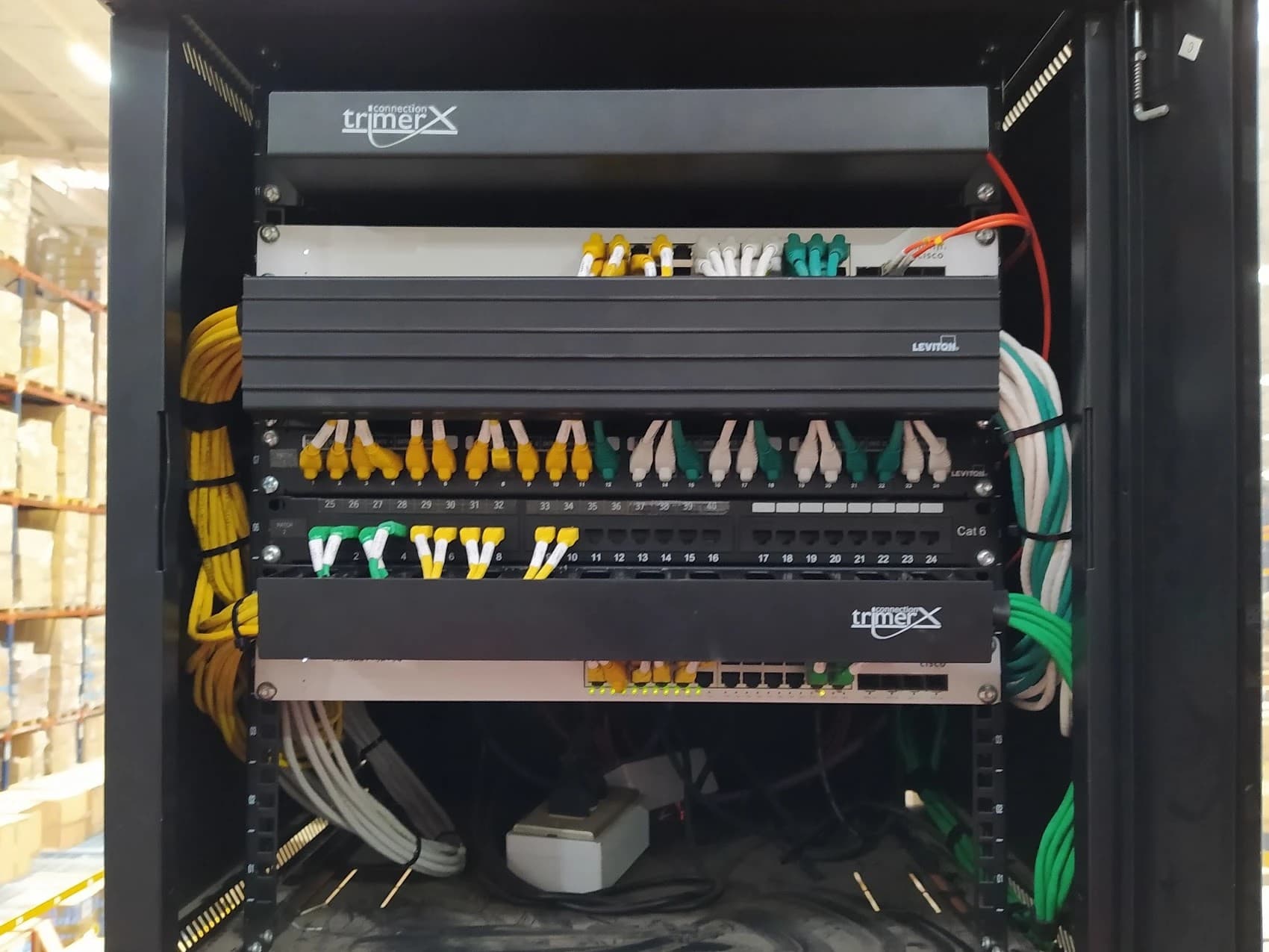 Gabinete con switches y patch panels, con patch cords amarillos, blancos y verdes según la red